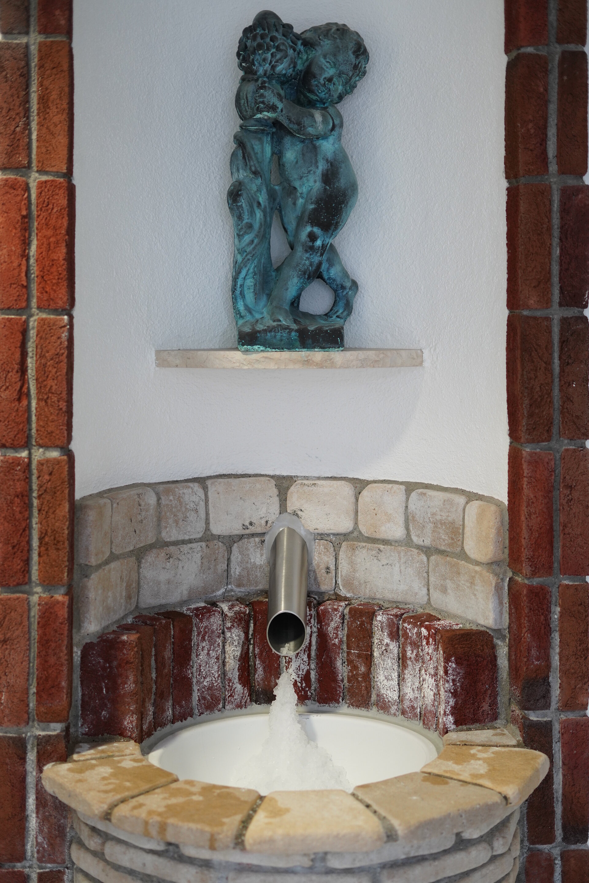 Das Bild zeigt einen Eisbrunnen, darüber ist eine Statue angebracht.