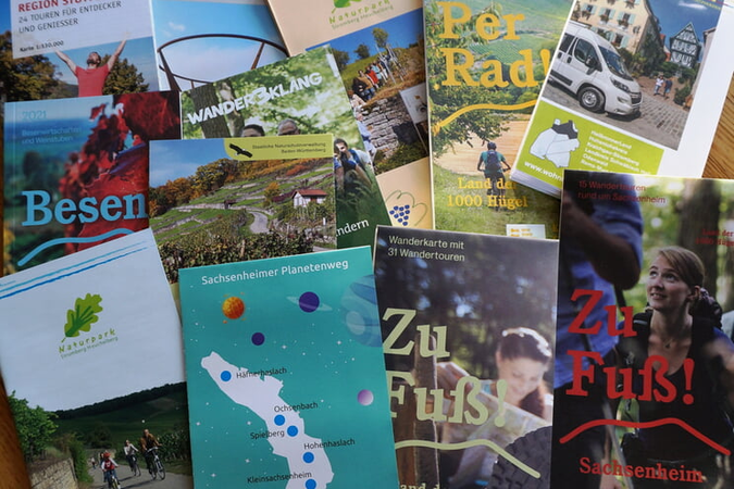Eine Auswahl verschiedener Tourismusbroschüren und Karten, die Aktivitäten wie Wandern und Radfahren in der Region bewerben.