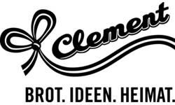 Das Bild zeigt ein Logo mit einem stilisierten, geschwungenen Schriftzug "Clement" neben einer Schleife, darunter steht in Großbuchstaben "BROT. IDEEN. HEIMAT.".