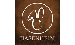 Das Bild zeigt ein stilisiertes Hasenkopf-Logo in einem Kreis, unter dem das Wort "HASENHEIM" steht, alles vor einem braunen Hintergrund.