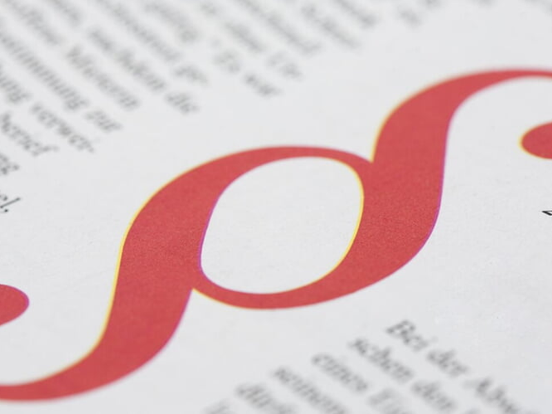 Ein großes, rotes Paragraphensymbol ist auf einem Dokument mit gedrucktem Text abgebildet.